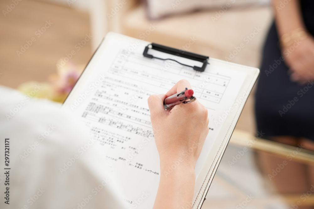 問診票にペンで記入している様子