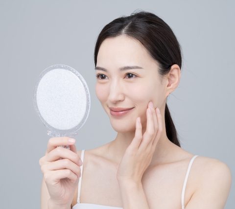 間の下の脂肪を鏡で見る女性