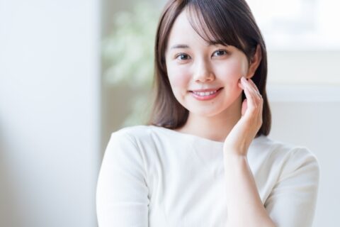 頬に左手を添えて微笑む日本人女性