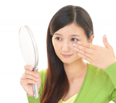 鏡で目の下 の 膨らみを見る女性
