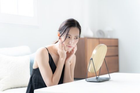 目の下のクマを鏡で確認する女性
