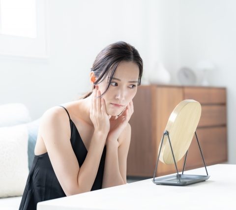 目の下のクマを鏡で確認する女性