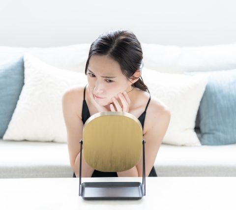 クマ取り整形失敗を気にして鏡を見ている女性