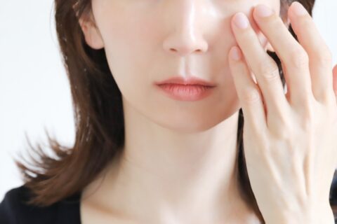目元に触れてクマを気にする女性の画像