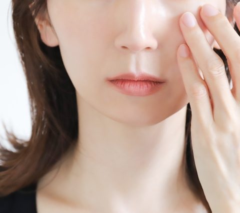 目元に触れてクマを気にする女性の画像
