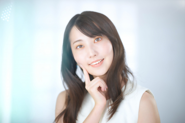 笑顔で頬に人差し指を充てる女性