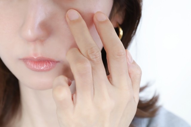 目元を押さえて目の下のクマを気にする女性