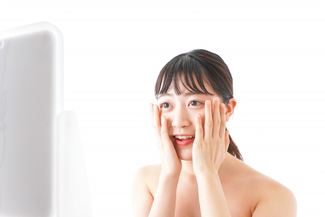 鏡の前でスキンケアをする女性