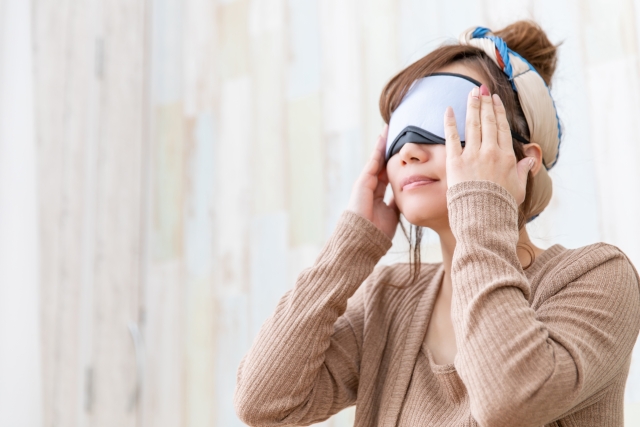 ホットアイマスクで目を温める女性