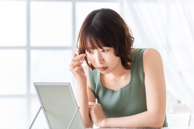 目元に指を当て鏡を見る女性