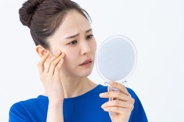 鏡を見て顔をしかめる女性