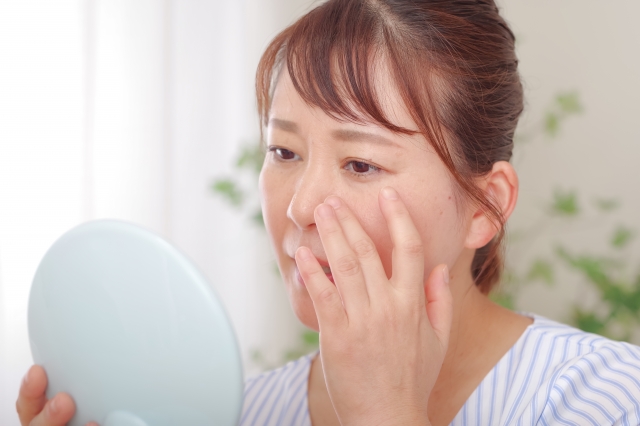 鏡で顔を見る女性